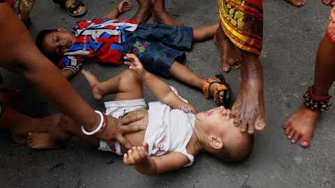 Un hombre santo hindú toca a un niño con su pie durante un ritual para bendecirlo, durante una procesión religiosa para conmemorar la festividad de Gajan en Calcuta.- RUPAK DE CHOWDHURI (REUTERS)