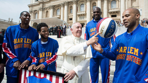 El Papa Francisco sonríe mientas juega con una pelota de baloncesto junto a un miembro del equipo de baloncesto Harlem Globotrotters en la plaza de San Pedro, en el Vaticano.- OSSERVATORE ROMANO / REUTERS