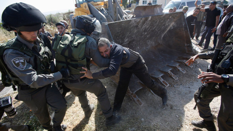 Policías israelíes forcejean con un hombre que intenta impedir el avance de un Bulldozer el el pueblo de Soba, cerca de la ciudad cisjordana de Hebrón.- MUSSA QAWASMA (REUTERS)