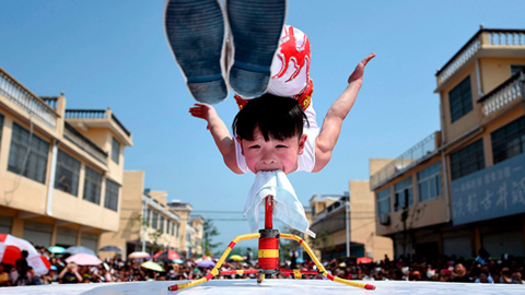 Un acróbata de seis años de edad lleva a cabo un ejercicio durante la apertura de un festival turístico en Bozhou, provincia de Anhui (China).- REUTERS