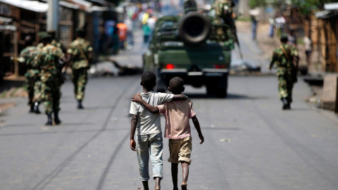 Dos niños caminan detrás de una patrulla de soldados en Bujumbrura (Burundi). Los militares intentaron un levantamiento militar hace dos días para poner fin a la ola de violencia desencadenada por la decisión de Nkurunziza de aspirar a un t