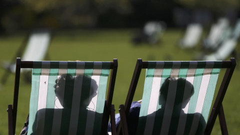 Dos personas aprovechan el buen tiempo de Londres para tomar el sol y relajarse. REUTERS/Neil Hall