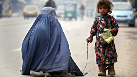 Una mujer ataviada con el burka y su hija piden lismona en una carretera de Peshawar, Pakistán. EFE/Arshad Arbab