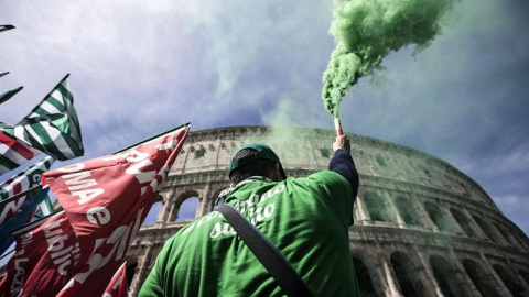 Un manifestante sujeta una bengala de humo frente al Coliseo de Roma durante una protesta convocada por los sindicatos coincidiendo con la huelga de empleados públicos, en Roma, Italia. EFE/Angelo Carconi