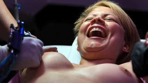 La superviviente de cáncer mamario Cyra Serracín (c), en manos del tatuador colombiano Fabian Henao, durante el proceso de realización de un tatuaje de pezón y aureola en Ciudad de Panamá (Panamá). EFE/Alejandro Bolívar