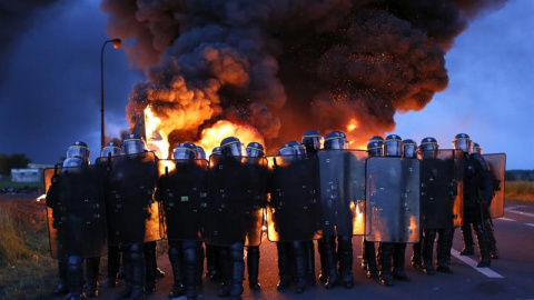 Agentes antidisturbios franceses avanzan delante de una barricada en llamas para proceder al desalojo de los manifestantes que bloquean la entrada a una refinería en Douchy-les-Mines, al noreste de Francia. EFE/Thibault Vandermersch