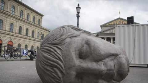 Una escultura gigante que representa la cabeza de la canciller alemana, Angela Merkel, yace en la plaza Max-Joseph-Platz delante de la Ópera en Múnich, Alemania. EFE/Peter Kneffel