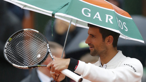 Novak Djokovic se refugia de la lluvia bajo un paraguas durante su partido contra Roberto Bautista en Roland Garros. REUTERS/Gonzalo