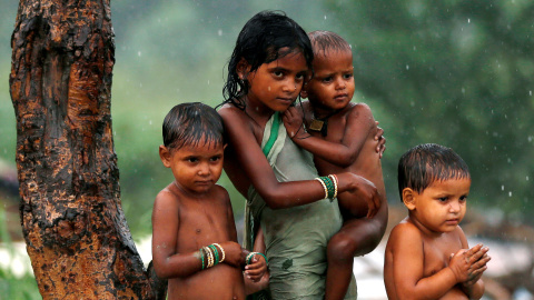 Unos niños se refugian de la lluvia bajo un árbol en Nueva Delhi, India. REUTERS/Adnan Abidi