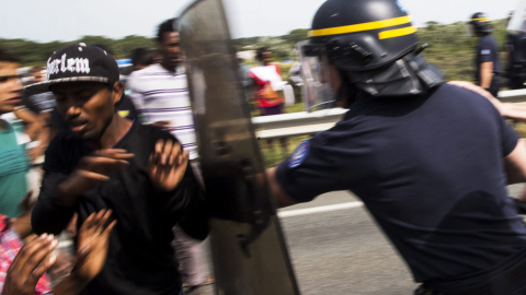 Varios policías se encaran a los inmigrantes del campamento conocido como "la jungla" junto a la carretera en Calais, Francia. EFE/Etienne Laurent