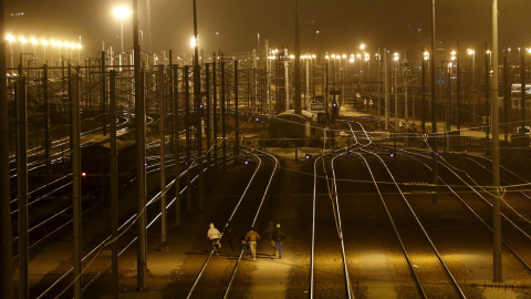Un grupo de inmigrantes corre entre las vías del tren para tratar de colarse y llegar a través del túnel de la Mancha hasta Reino Unido. REUTERS/Juan Medina