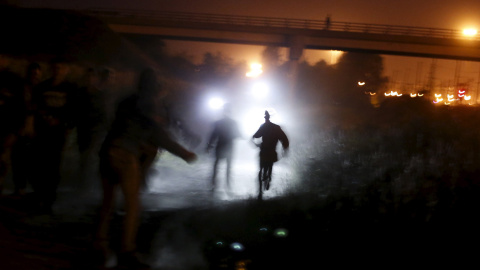 La policía francesa apunta con sus linternas a un grupo de inmigrantes en un intento de cruzar a Inglaterra a través del túnel de la Mancha, en Calais, Francia. REUTERS/Juan Medina