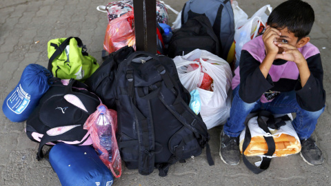 Un niño que huye de la guerra de Siria espera junto a todas sus pertenencias en Kanizsa, Serbia. REUTERS/Laszlo Balogh
