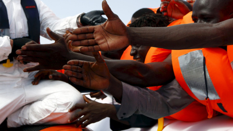 Un grupo de inmigrantes extiende la mano a la espera de ser rescatados frente a la costa de Libia. REUTERS/Darrin Zammit Lupi