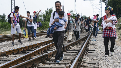 Inmigrantes caminan sobre las vías antes de tomar un tren con destino a  la frontera serbia en la localidad de Gevgelija, Macedonia EFE/Georgi Licovski