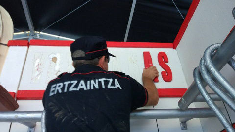 Un ertzaina retira la decoración de la comparsa anarquista Hontzak Un ertzaina retira la decoración de la comparsa anarquista Hontzak