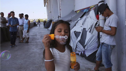 Una niña afgana juega con pompas de jabón en el campamento de refugiados de Hellinikon, en Atenas (Grecia). Unos 57.000 refugiados están acogidos en alguno de los campamentos distribuidos por el país. EFE/Orestis Panagiotou