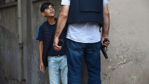 Un oficial de la Policía de Turquía hace preguntas a un niño kurdo después de un atentado contra agentes de la Policía turca en el centro de Diyarbakir, el 23 de julio de 2015. Un miembro del cuerpo fue abatido a tiros y hubo un segundo her