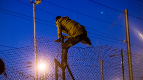 Un inmigrante escala una valla de acceso al túnel del Canal de La Mancha, en Frethun, al norte de Francia.- AFP PHOTO / PHILIPPE HUGUEN