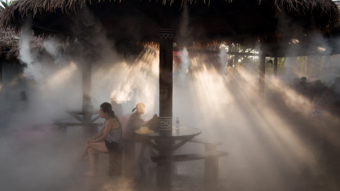 La gente se refresca debajo de un aspersor en un parque acuático en Shanghai.- AFP PHOTO / JOHANNES EISELE