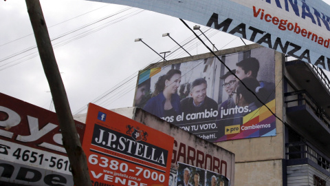 La gente camina debajo de un banner de publicidad del candidato presidencial Scioli y del candidato presidencial de Macri en La Matanza . REUTERS / Marcos Brindicci