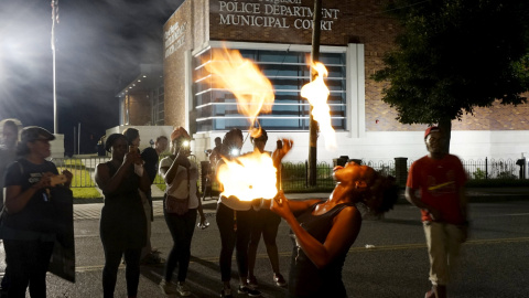 Laura Charles realiza juegos con palos de fuego durante una protesta fuera del departamento de policía de Ferguson por el aniversario de los disturbios de Ferguson. REUTERS / Rick Wilking