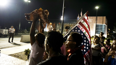 Manifestantes sostienen una cabeza de cerdo de un asado de cerdo fuera del departamento de policía de Ferguson. REUTERS / Rick Wilking