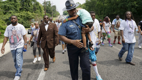 El capitán Ron Johnson de la patrulla Estatal de Missouri lleva durmiendo a un niño pequeño llamado Edwards durante una marcha de protesta en Ferguson. REUTERS