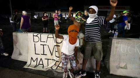 Tres manifestantes jóvenes, entre ellos un niño de tres años de edad, protestan fuera del departamento de policía de Ferguson. REUTERS