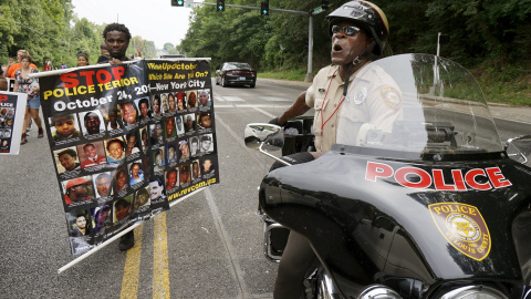 Un oficial de policía del condado de San Luis mantiene conversaciones desde su moto con los manifestantes en una marcha de protesta en Ferguson. REUTERS