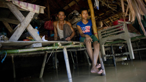 Unos habitantes se sientan dentro de su casa afectada por las inundaciones en el pueblo de Kyaut Ye cerca del pueblo de Hinthada en la región de Irrawaddy de Myanmar, el 10 de agosto de 2015. AFP PHOTO / Ye Aung
