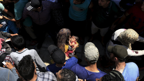Hombres sirios forman una barrera de seguridad para las mujeres por los enfrentamientos durante un procedimiento de registro en el estadio nacional de la isla griega de Cos, 11 de agosto 2015./ REUTERS/ Yannis Behrakis