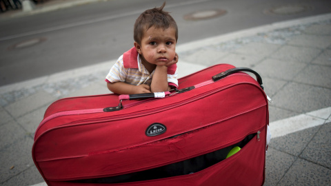 Un niño espera a sus padres apoyado en su maleta al salir de la Oficina Estatal de Salud y Asuntos Sociales de Berlín con otros refugiados recién llegados que esperaron todo el día para solicitar el asilo en Berlín. REUTERS / Stefanie Loos