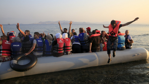 Refugiados sirios saltan de alegría al llegar a una playa en la isla griega de Cos, 11 de agosto de 2015.REUTERS/ Yannis Behrakis