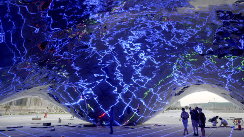 Gente mirando la prueba de iluminación dentro de una nueva escultura con forma de burbuja gigante de petróleo, en un complejo turístico construido cerca del primer pozo de perforación del yacimiento Karamay, Región Autónoma Uigur, China. RE