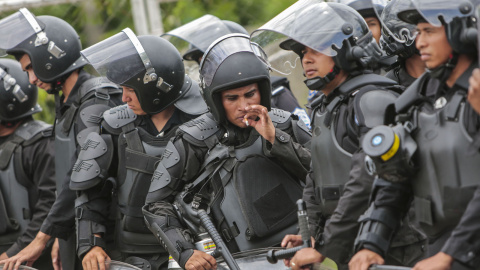 Un policía antidisturbios fuma un cigarrillo durante una protesta contra el sistema electoral, en Managua, el 12 de agosto de 2015. AFP PHOTO / Inti OCON
