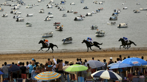 Jinetes cabalgan durante una tradicional carrera por la playa de Sanlúcar de Barrameda, en el sur de España, 12 de agosto de 2015. REUTERS / Marcelo del Pozo