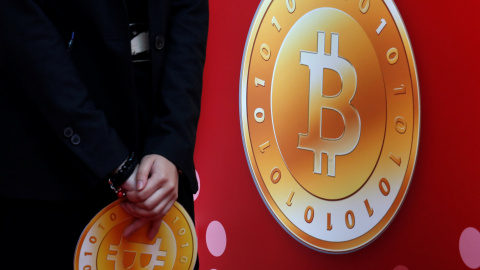 Un empleado de la tienda bitcoin de Hong Kong sostiene el logo de la moneda virtual. REUTERS/Bobby Yip Un empleado de la tienda bitcoin de Hong Kong sostiene el logo de la moneda virtual. REUTERS/Bobby Yip