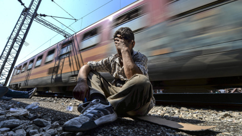 Un inmigrante exhausto y frustrado tras no poder conseguir una plaza en un tren que se dirige a la frontera con Serbia en la estación de tren de Gevgelija (Macedonia) hoy, 13 de agosto de 2015. EFE/Georgi Licovski