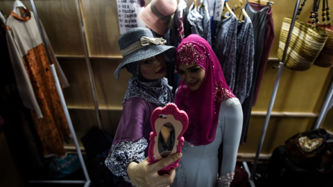 Modelos haciéndose selfies mientras esperan el backstage antes del inicio de la pasarela de moda islámica durante la semana de moda de Kuala Lumpur 2015. AFP PHOTO / MANAN VATSYAYANA