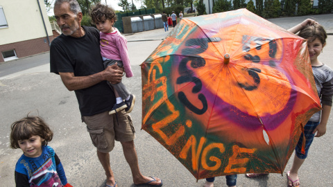 Un joven sirio solicitante de asilo lleva un paraguas decorado con las palabras: " Un corazón para los refugiados " en el centro " Zentrale Aufnahmestelle für Asylbewerber ", en Eisenhuettenstadt, al este de Alemania. JOHN MACDOUGALL / AFP