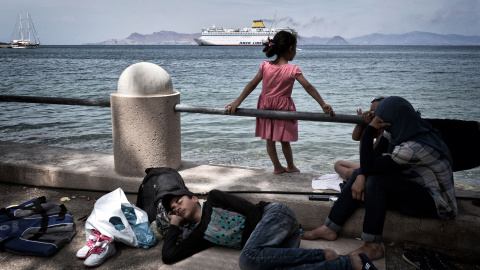 Inmigrantes sirios ven la llegada del ferry de Eleftherios Venizelos desde el campamento improvisado en la costa de la isla griega de la isla de Cos , el 14 de agosto de 2015. AFP PHOTO / LOUISA GOULIAMAKI