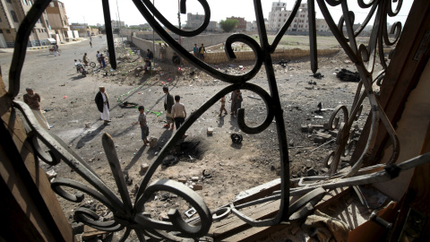 Se ven peatones desde una ventana de una casa, cerca del sitio del coche bomba que explotó el jueves en la capital de Yemen, Saná 14 de agosto de 2015. No hubo víctimas de la explosión. REUTERS / Mohamed al- Sayaghi