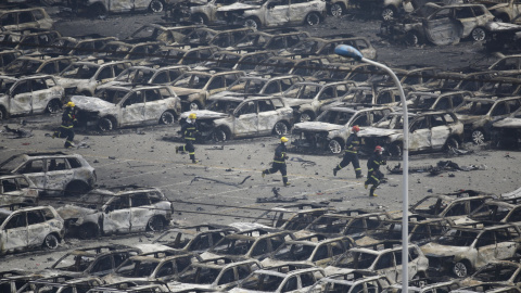Los bomberos corren como entre coches calcinados en el lugar de las explosiones que han causado decenas de muertos en la ciudad de Tianjin, China.- REUTERS / Jason Lee