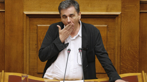 El ministro de Finanzas griego, Euclides Tsakalotos, bosteza mientras varios diputados intentan interrumpir su discurso en un debate que se prolongó durante toda la noche para aprobar el tercer rescate a Grecia.-REUTERS / Christian Hartmann