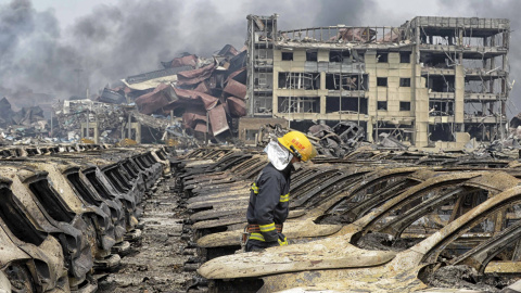 Un bombero, entre vehículos calcinados junto al almacén incendiado. - REUTERS Un bombero, entre vehículos calcinados junto al almacén incendiado. - REUTERS