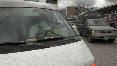 Un hombre lleva mascarilla mientras conduce su coche cubierto de ceniza volcánica en Machachi./ REUTERS