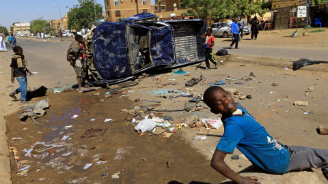 Varios niños juegan cerca de un coche de la policía volcado y dañado por los familiares de un manifestante que murió de una herida de bala durante las protestas antigubernamentales en Jartum, Sudán.-REUTERS / Mohamed Nureldin Abdallah