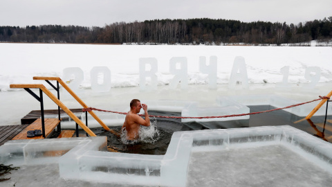 Un hombre toma un baño en las aguas heladas de un lago en la víspera de la Epifanía Ortodoxa cerca del pueblo de Pilnitsa, Bielorrusia.- REUTERS / Vasily Fedosenko