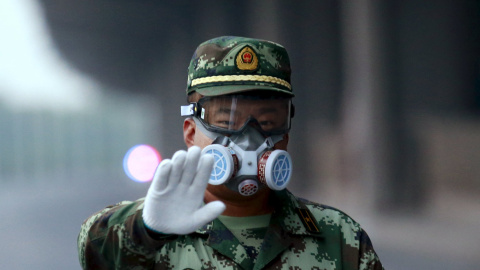 Un policía paramilitar que lleva una máscara de gestos al fotógrafo para dejar como él bloquea una carretera que conduce a la zona residencial evacuadas y lugar de la explosión, en el nuevo distrito de Binhai en Tianjin, China, 17 de agosto